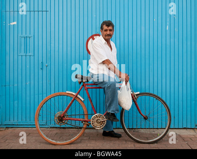 Man on bicycle in front of blue wall, Tonalá, Mexico. Stock Photo