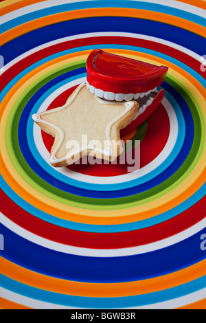 Teeth holding star cookie on circle plate Stock Photo