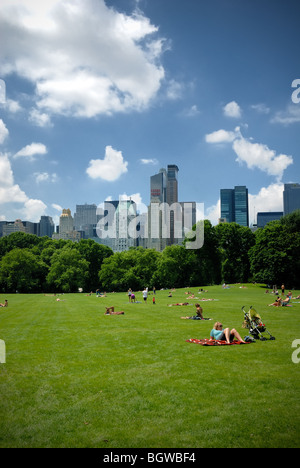 People relax on the grass in Central Park, New York city, overlooking the New York skyline. Stock Photo