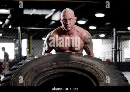 Strong man lifting a tire. Stock Photo