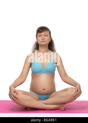 Pregnant young woman meditating in Lotus pose with closed eyes Stock Photo