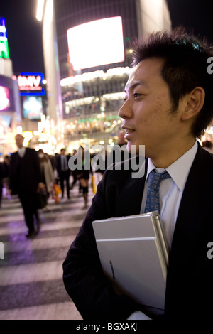 Young Japanese salaryman business man with laptop, at Shibuya crossing, Tokyo, Japan. Stock Photo
