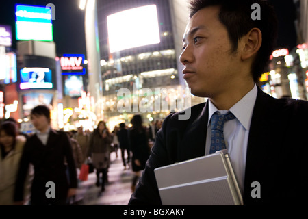 Young Japanese salaryman business man with laptop, at Shibuya crossing, Tokyo, Japan. Stock Photo