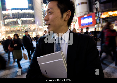 Young Japanese salaryman business man with laptop, at Shibuya crossing, Tokyo, Japan. Stock Photo