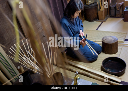 Yoshida Mino, apprentice bamboo artisan with the Tanabe family, splitting bamboo by hand in the workshop in the Tanabe studio. Stock Photo