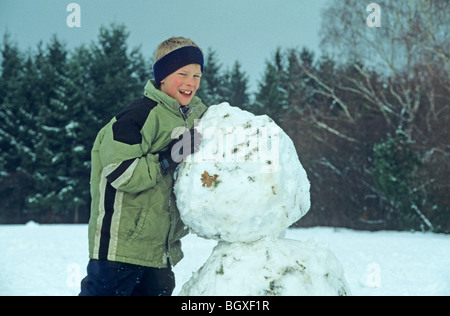young boy building a snowman Stock Photo