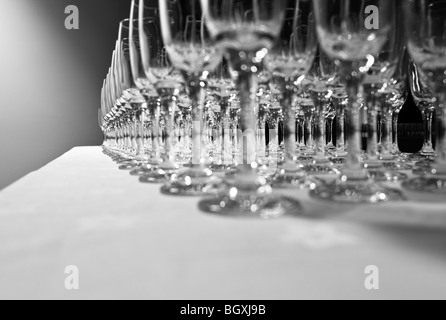 Rows of empty wine glasses lined up on a table with a white cloth in preparation for a perty Stock Photo