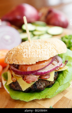 Burger being prepared, with cheese, bacon and garnish in a restaurant Stock Photo