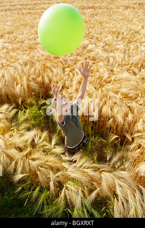 Boy playing with balloon in wheat field Stock Photo