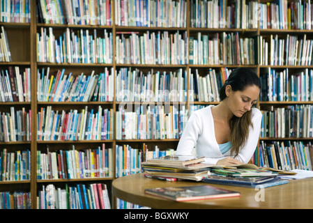 Woman reading book at table in library Stock Photo