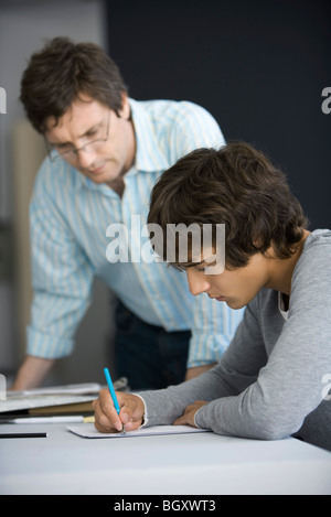 College student working on assignment, teacher assisting Stock Photo