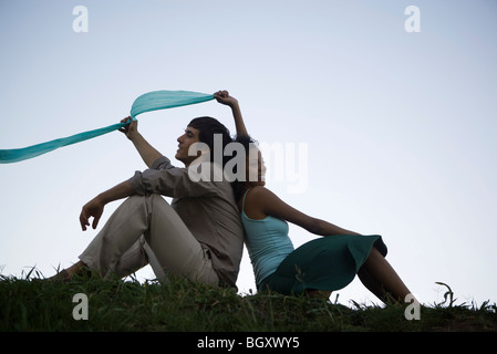 Young couple sitting in grass back to back Stock Photo