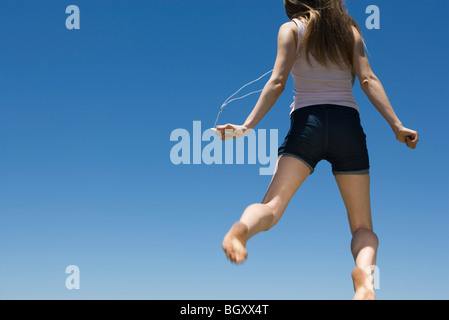 Young woman listening toMP3 player, jumping in midair Stock Photo