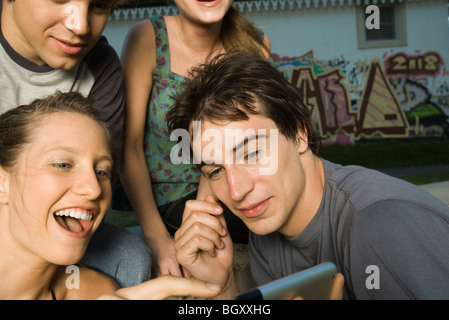 Friends enjoying wireless media displayed on mobile device Stock Photo