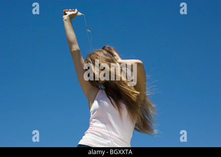 Young woman listening to MP3 player, dancing outdoors