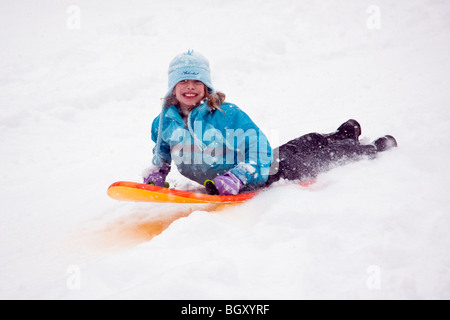 Child sledding in a fresh snowfall. Stock Photo