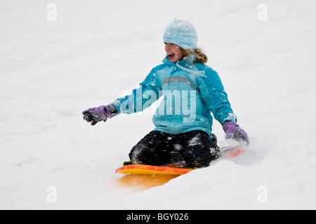 Child sledding in a fresh snowfall. Stock Photo