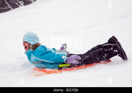 Child sledding in a fresh snowfall. Stock Photo