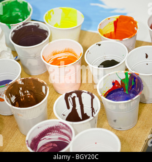 Plastic cups full of children's paint on a wooden table Stock Photo