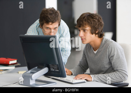 Teacher assisting student with computer assignment Stock Photo