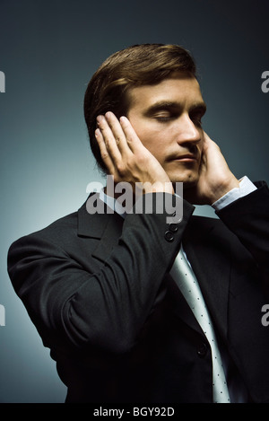 Businessman with hands covering ears and eyes closed Stock Photo