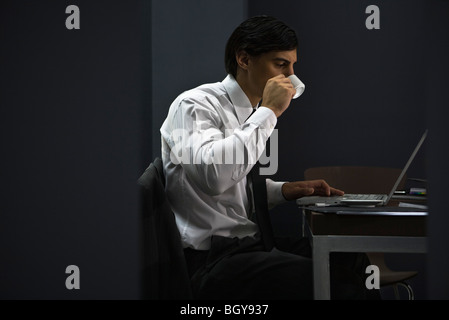 Man in office drinking coffee, working late Stock Photo