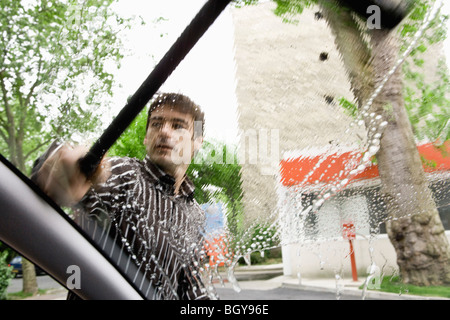 Man washing car windshield with squeegee Stock Photo