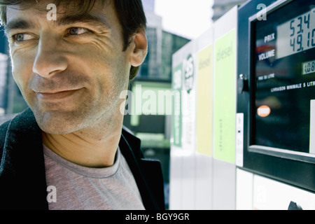 Man finishing at gas pump preparing to leave Stock Photo