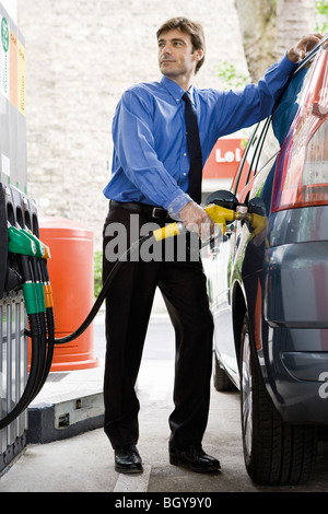Well-dressed man refueling vehicle at gas station Stock Photo
