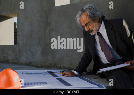 Architect studying blueprint at construction site Stock Photo