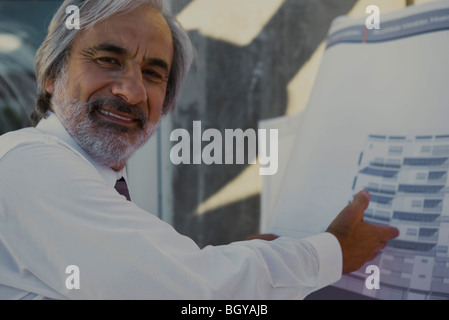 Architect showing blueprint, smiling over shoulder at camera Stock Photo