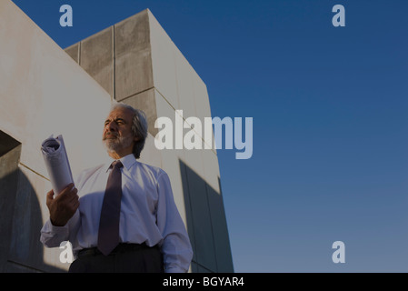 Architect standing in front of building with blueprint under arm, low angle view Stock Photo