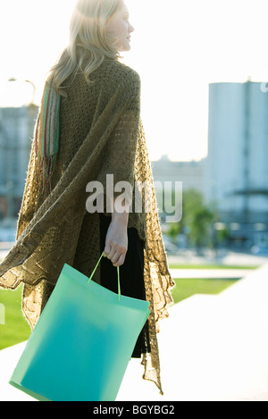 Woman carrying shopping bag, walking through park Stock Photo