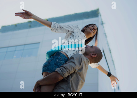 Man lifting woman in air, woman's arms outstretched Stock Photo