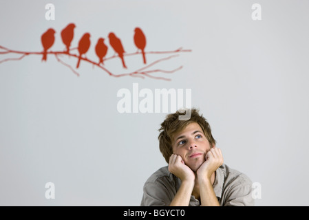 Young man daydreaming, chin resting on hands Stock Photo