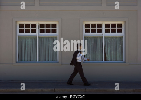 Young man in business attire walking on sidewalk, side view Stock Photo