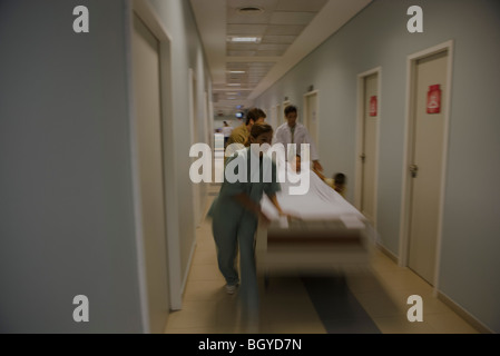Healthcare workers running with patient on gurney in hospital corridor Stock Photo