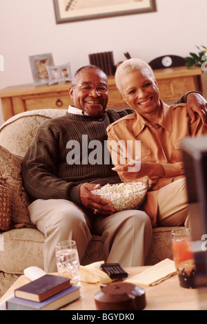 Couple on couch eating popcorn Stock Photo