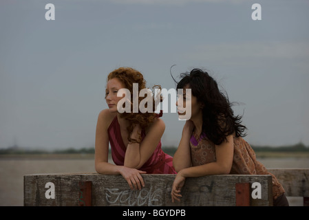 Two young women outdoors, leaning on railing, looking away Stock Photo