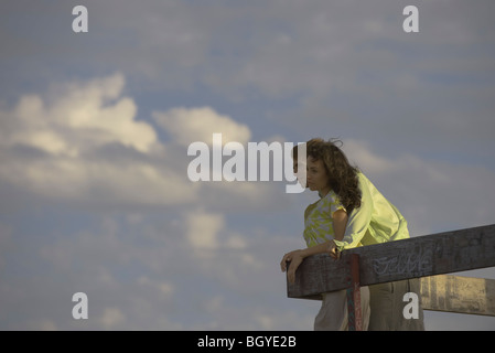Young couple leaning against railing, looking into distance, clouds in background Stock Photo