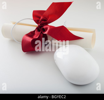 Red ribbon on diploma beside computer mouse Stock Photo