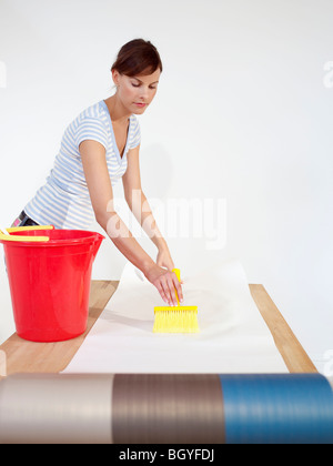 Woman brushing paste onto wallpaper Stock Photo
