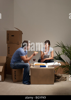 Couple eating pizza on cardboard box Stock Photo