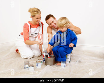 Couple and boy mixing paint in bucket Stock Photo