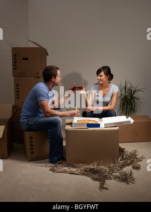 Couple eating pizza on cardboard box Stock Photo