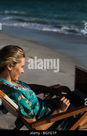 Woman using laptop computer at beach Stock Photo