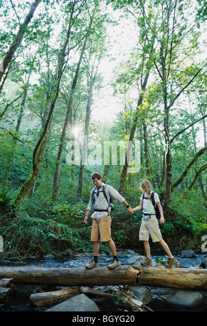 Hikers walking on log Stock Photo