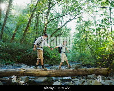 Hikers walking on log Stock Photo