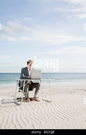Businessman working at desk on the beach Stock Photo