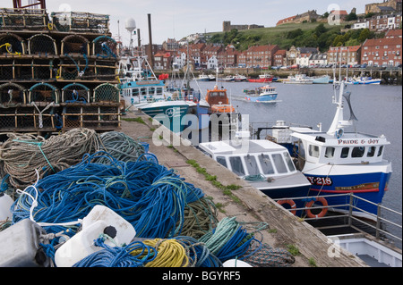 Fishing nets on the quayside and boats moored in Whitby's outer harbour. Stock Photo